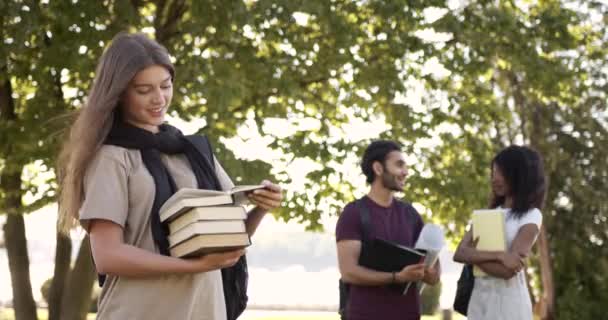 Female student with books classmates talking beside — Vídeo de Stock