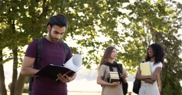 Male student holding notebook and girls talking at campus — Stock videók