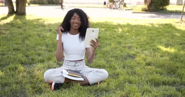 Joyful black woman listening to music on tablet in park in sunny day — Stok Video