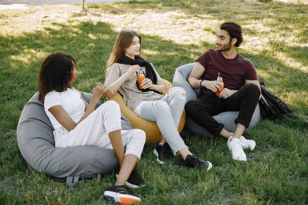 Three friends talking while sitting on the bean bag chairs in a park — Zdjęcie stockowe
