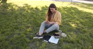 Young woman using phone sitting on lawn