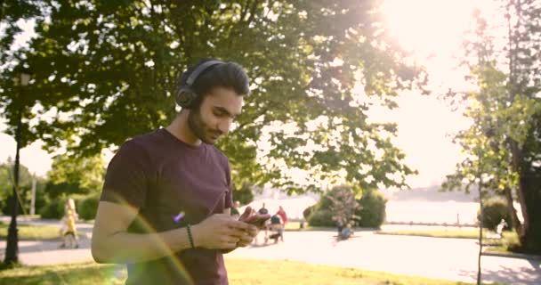 Pakistani young man listening to music in a green park — Video Stock