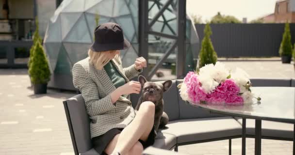 Young casually dressed woman sitting at cafe with her bulldog puppy — Video Stock