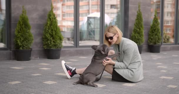 Young stylish woman and cute bulldog outdoors — Stock video