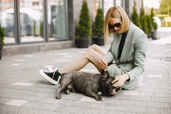 Blonde girl sitting on a pavement with black French bulldog pupp — Stockfoto