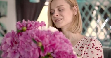 Pretty blonde woman holding a bunch of peonies