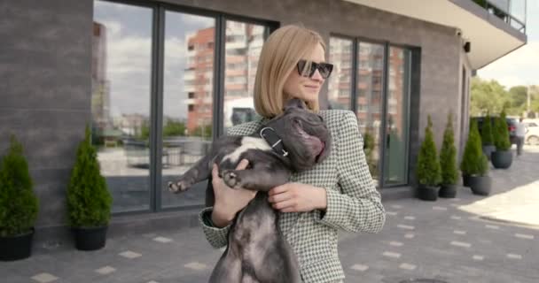 Young woman with cute french bulldog at building — Stockvideo