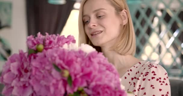 Pretty blonde woman holding a bunch of peonies — Vídeo de stock
