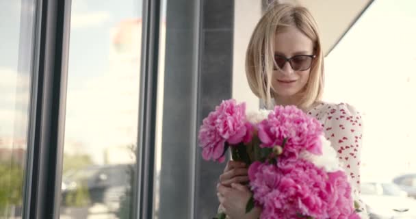 Pretty blonde woman holding a bunch of peonies — Stockvideo