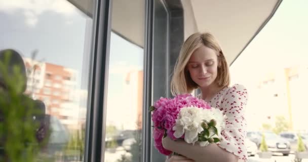 Pretty blonde woman holding a bunch of peonies — Vídeo de stock
