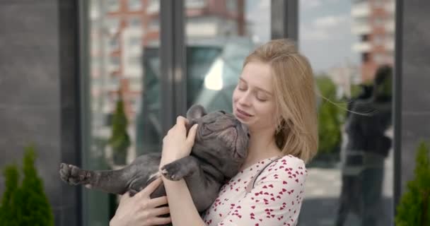 Beautiful young girl holding adorable French bulldog puppy — Stockvideo