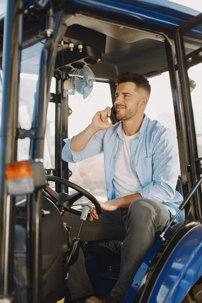 Hombre sentado cómodamente en un tractor azul grande —  Fotos de Stock