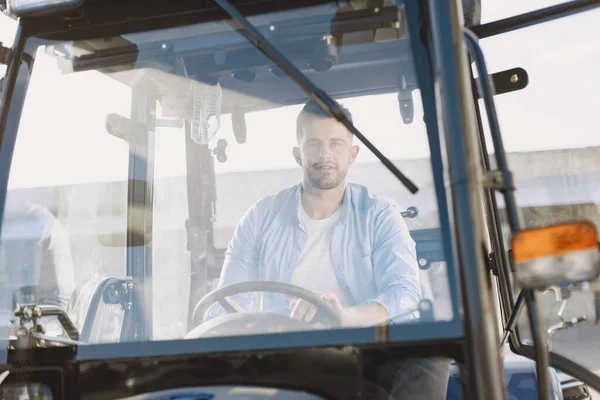 Hombre sentado cómodamente en un tractor azul grande —  Fotos de Stock