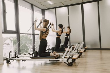 Three girls in a bright gym doing functional training with equipment