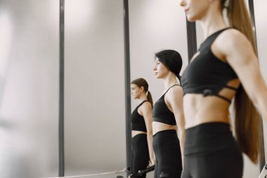 Three girls in a bright gym doing functional training with equipment