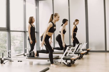 Three girls in a bright gym doing functional training with female trainer