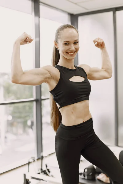 Fit woman with pony tail shows arm muscles, biceps and triceps — Stockfoto