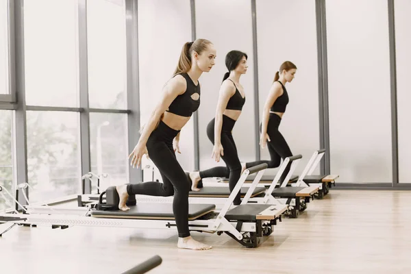 Three girls in a bright gym synchronously stretching with equipment — 스톡 사진