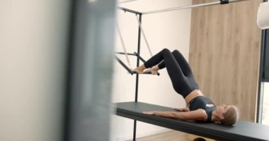 Young girl doing pilates exercises with a reformer bed
