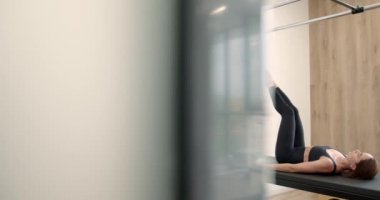 Young girl doing pilates exercises with a reformer bed