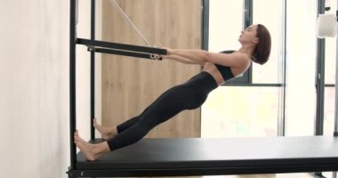 Young girl doing pilates exercises with a reformer bed