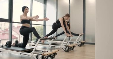 Three women doing pilates on a reformer bed