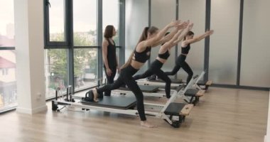 Three women doing pilates on a reformer bed