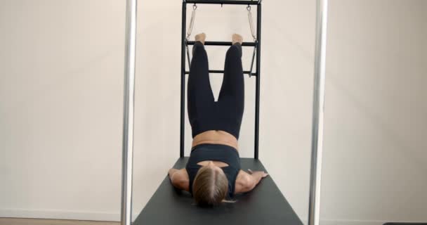 Young girl doing pilates exercises with a reformer bed — Wideo stockowe