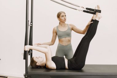 Young woman streching muscles with a female trainer