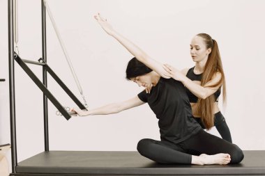 Young woman streching muscles with a female trainer