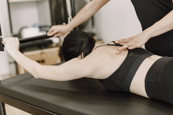 Young woman streching muscles with a female trainer — Fotografia de Stock