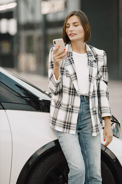 Ritratto di una giovane donna bruna che usa un cellulare vicino alla sua auto — Foto Stock