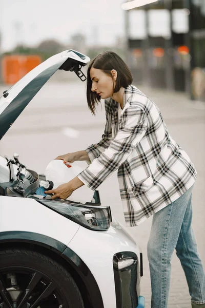 Portrait of a young brunette woman pouring some fluid in her cars engine — Foto Stock