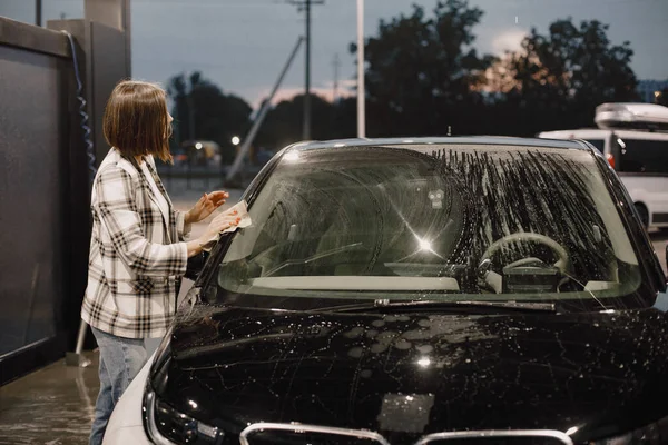 Donna che lava la sua auto con un tappeto nella stazione di lavaggio auto — Foto Stock