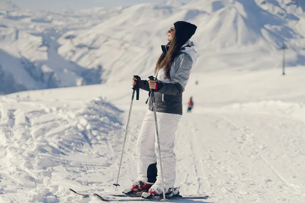 Młoda i aktywna brunetka na nartach w zaśnieżonych górach — Zdjęcie stockowe