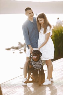 Portrait of a romantic couple with their rotweiller near the lak