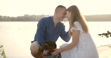 Loving young couple with a dog by lake