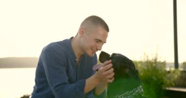 Young man spending time with his dog be river bank