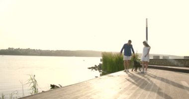 Young European couple going near lake with dog