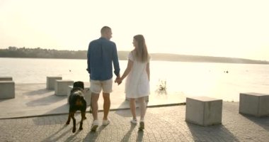 Young European couple going near lake with dog