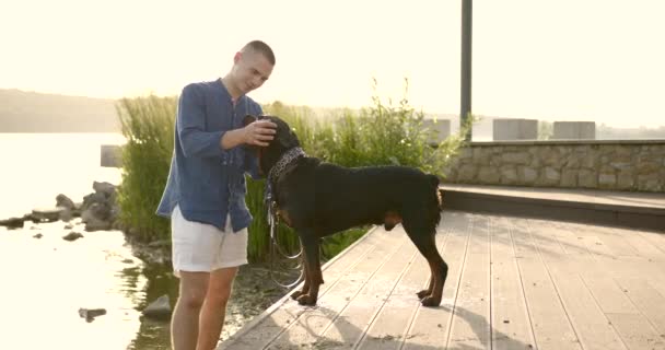 Young man spending time with his dog be river bank — kuvapankkivideo