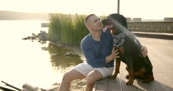 Young man spending time with his dog be river bank — kuvapankkivideo