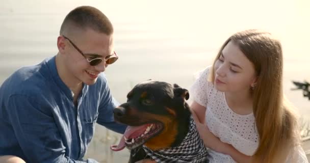 Loving young couple with a dog by lake — kuvapankkivideo