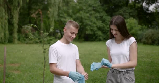 Jóvenes voluntarios que se ponen guantes de goma al aire libre — Vídeos de Stock