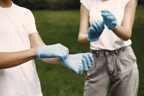 Mladí dobrovolníci si navlékají gumové rukavice venku — Stock fotografie