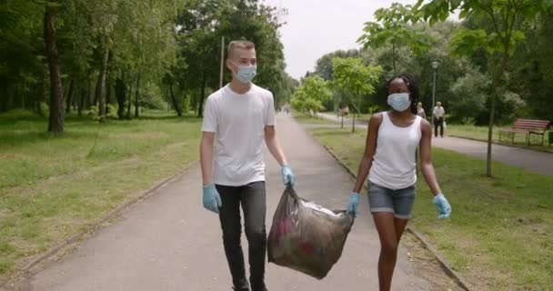 I volontari adolescenti trasportano sacchi della spazzatura in un parco — Video Stock