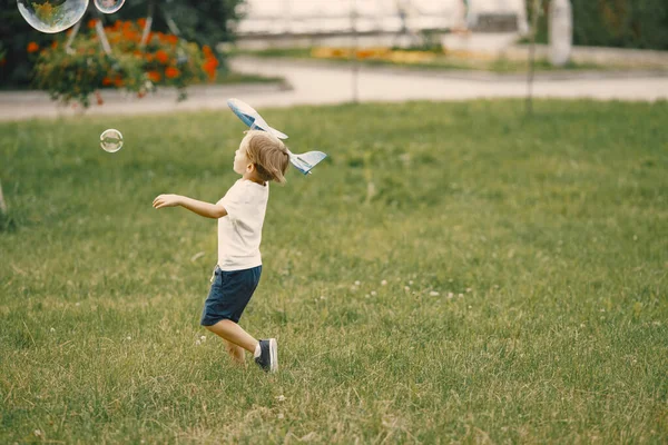 Μικρό αγόρι παίζει με το παιχνίδι αεροπλάνο σε ένα γρασίδι — Φωτογραφία Αρχείου