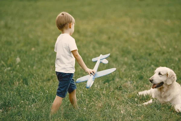 Kleine jongen spelen met vliegtuig speelgoed en zijn hond op een gras — Stockfoto