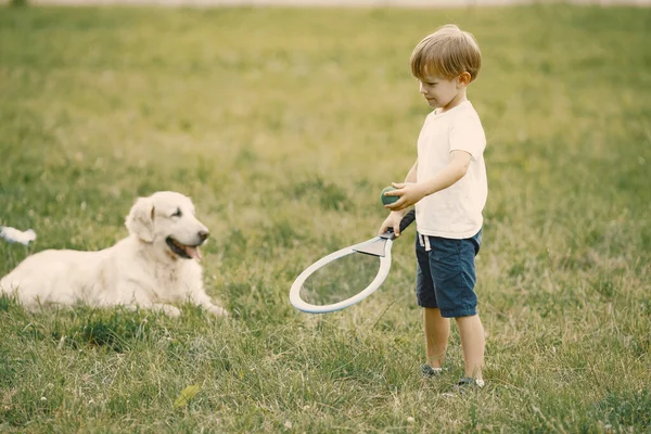 Petit garçon faisant une bulle de savon géant tout en jouant avec son chien sur une herbe — Photo