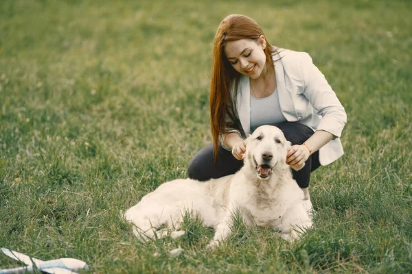 Jonge vrouw zitten met haar hond op een gras — Stockfoto